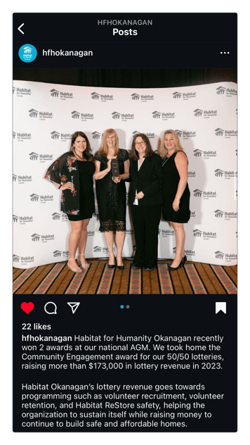 Four individuals stand smiling in front of a white wall, posing for a picture. They are all holding an award plaque together, displaying their accomplishment